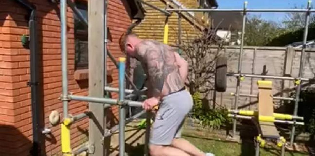 Man bouwt leipe thuis gym van steigers zodat hij kan blijven sporten